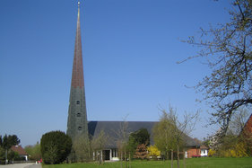 Außenansicht der Paul-Gerhardt-Kirche mit umliegenden Bäumen und Wiese