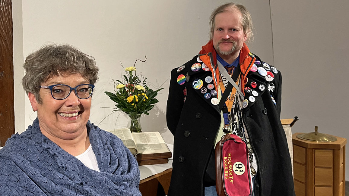 Eine Frau und ein Mann stehen vor einem Altar und lächeln.