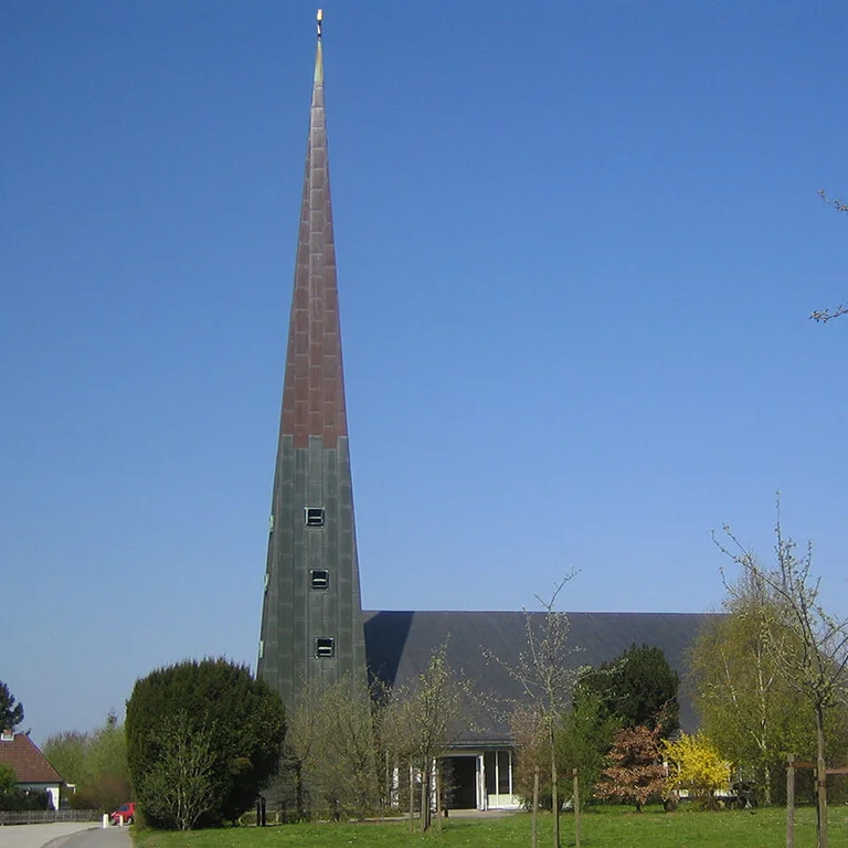 Außenansicht der Paul-Gerhardt-Kirche mit umliegenden Bäumen und Wiese