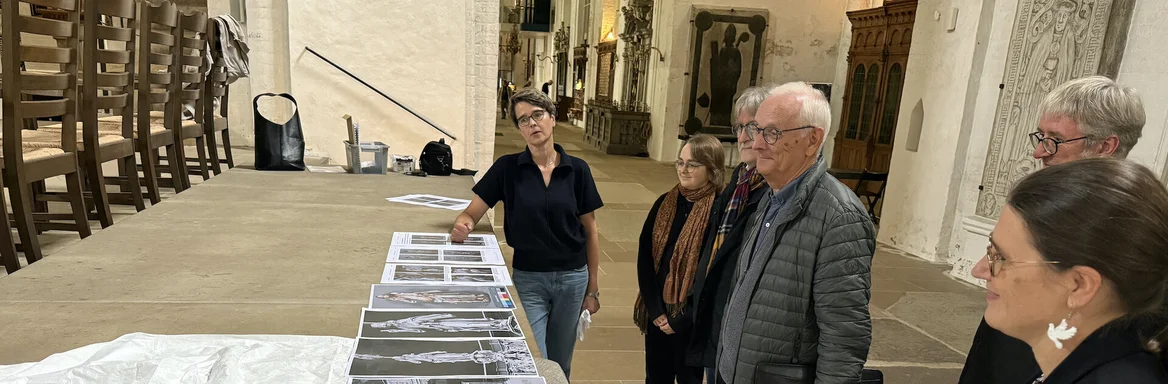 Mehrere Personen stehen in einer Kirche an einem Tisch mit Fotos und einer Jesus-Figur.