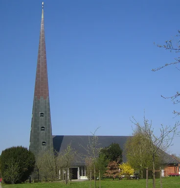 Außenansicht der Paul-Gerhardt-Kirche mit umliegenden Bäumen und Wiese