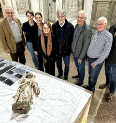 Gruppenfoto vor einem Tisch mit Fotos und einer liegenden Jesus-Figur.